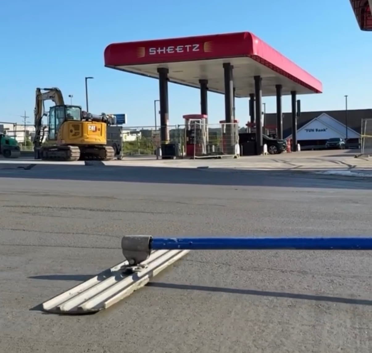 Concrete bull float at a Sheetz gas station construction site with a yellow excavator.